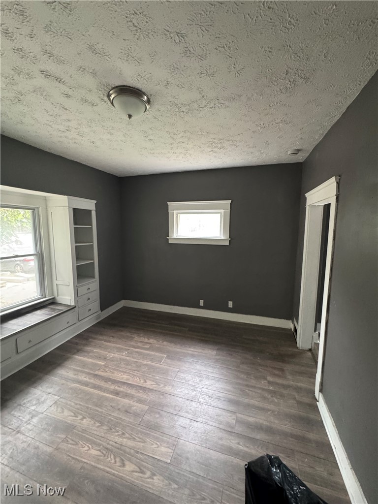 411 Eddy Road Cleveland, OH 44108 - Photo 3 of 8 Empty room with a textured ceiling and dark wood-type flooring