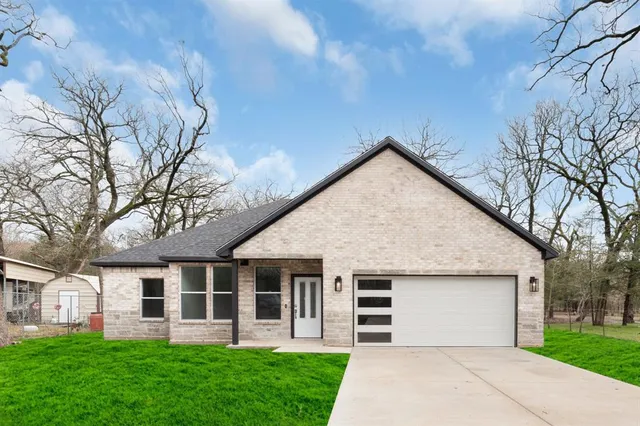 a view of a house with a yard and large tree
