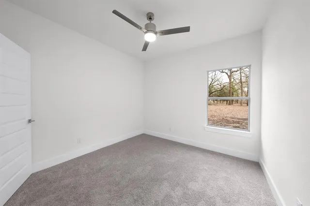 an empty room with a window and a ceiling fan