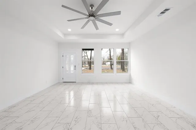 an empty room with windows and ceiling fan