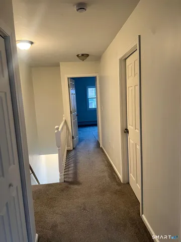 a view of a hallway with wooden floor and staircase