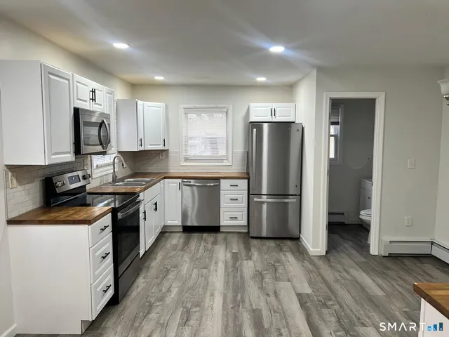 a kitchen with a refrigerator a stove top oven and white cabinets