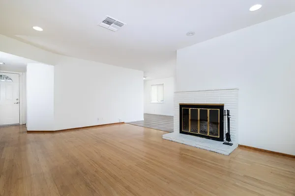a view of empty room with wooden floor and fireplace