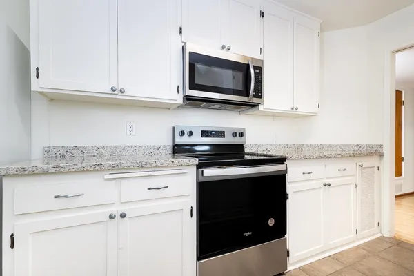 a kitchen with stainless steel appliances granite countertop white cabinets granite counter tops and a hard wood floors