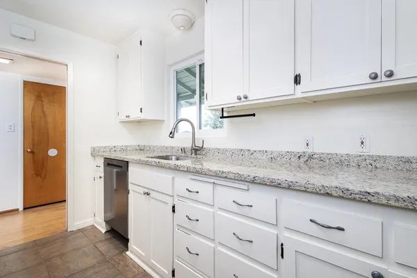 a kitchen with granite countertop white cabinets and a sink
