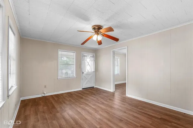 an empty room with windows and a chandelier fan