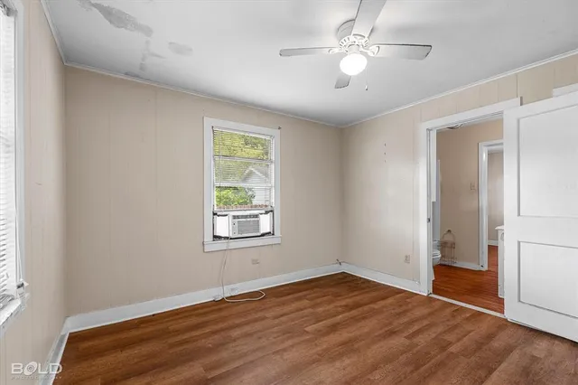 a view of empty room with wooden floor and fan