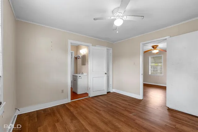 an empty room with wooden floor and a ceiling fan