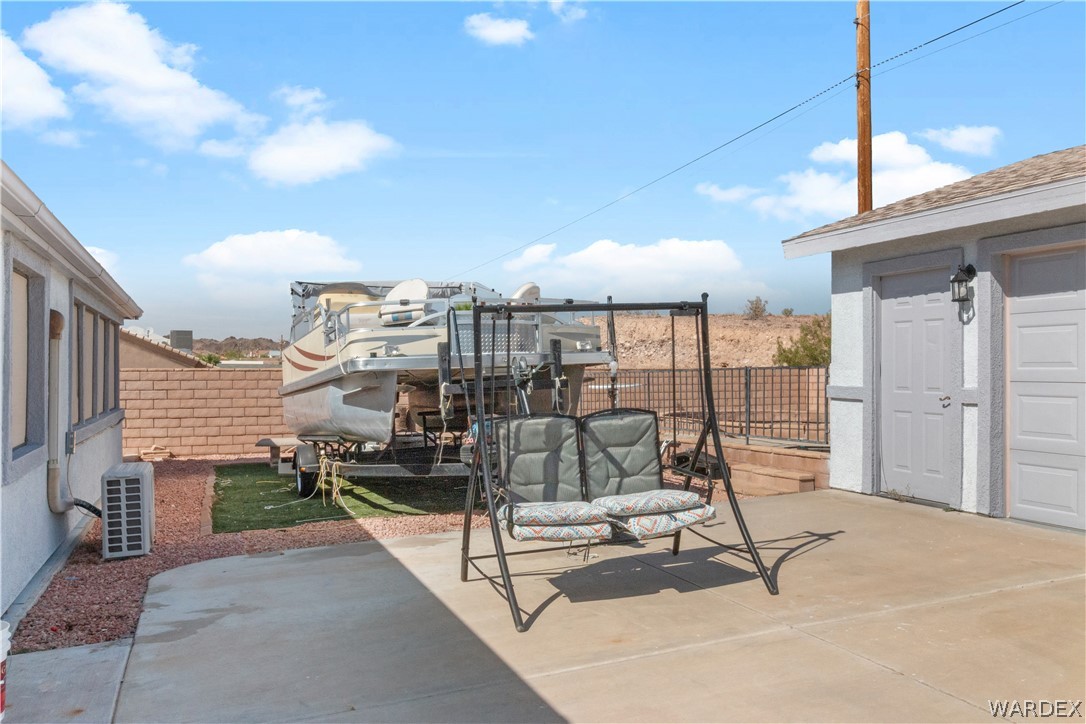 784 Pegasus Ranch Road Bullhead City, AZ 86429 - Photo 81 of 100 Paved concrete patio area with a two-car garage featuring panel-style doors and exterior lighting