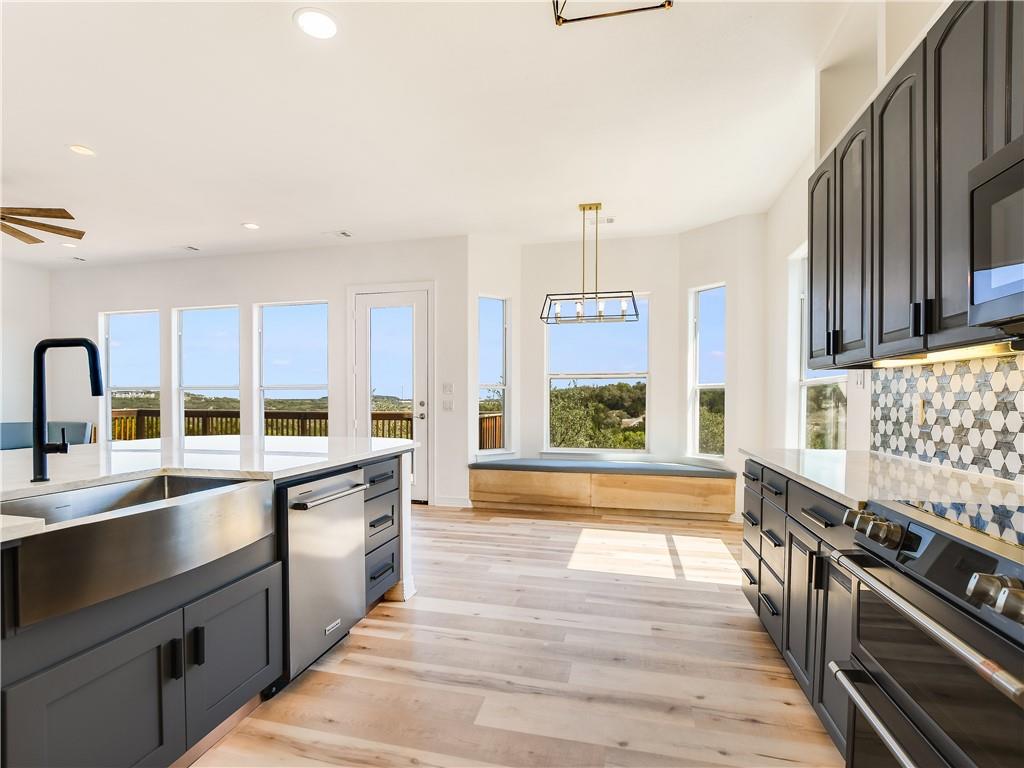 The kitchen features light wood flooring, dark cabinetry, and light countertops
