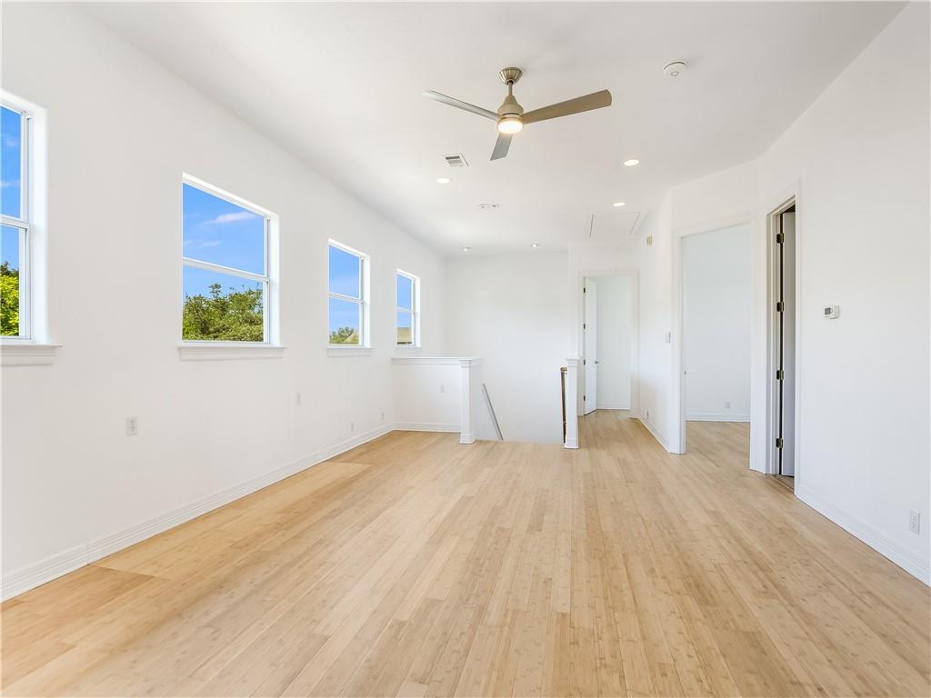 13301 Lone Rider Trail Bee Cave, TX 78738 - Photo 13 of 21 Bright living area featuring light-toned wood flooring, multiple windows, and a ceiling fan