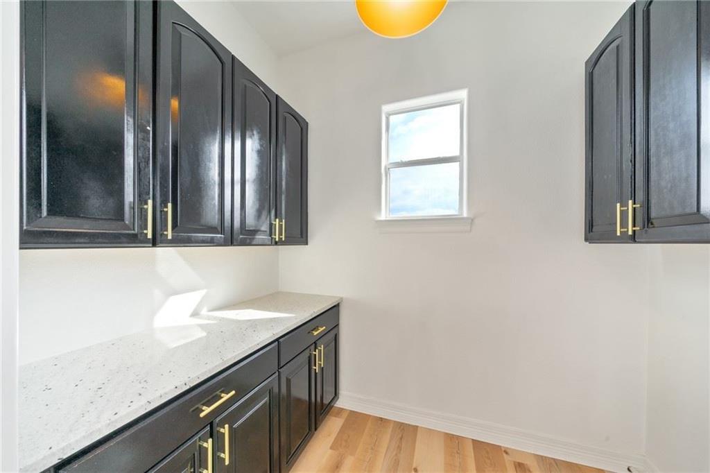 13301 Lone Rider Trail Bee Cave, TX 78738 - Photo 14 of 21 This utility space features black cabinetry with gold hardware, light-colored countertops, and light wood flooring