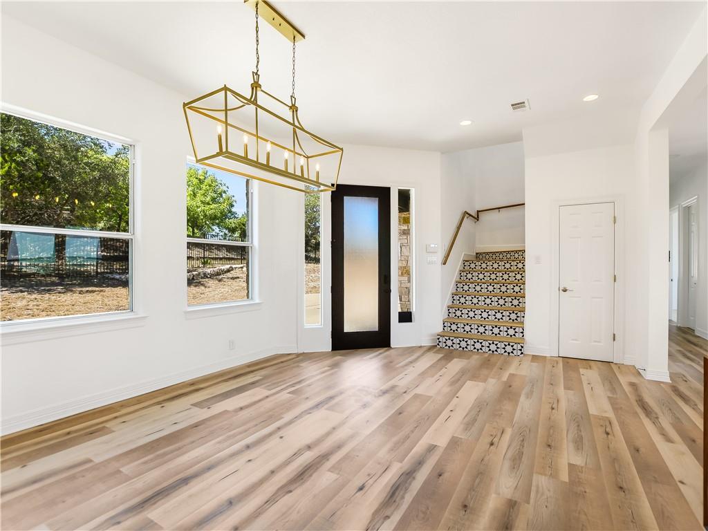 13301 Lone Rider Trail Bee Cave, TX 78738 - Photo 7 of 21 The interior features wide plank flooring, a modern linear chandelier, and a staircase with patterned risers