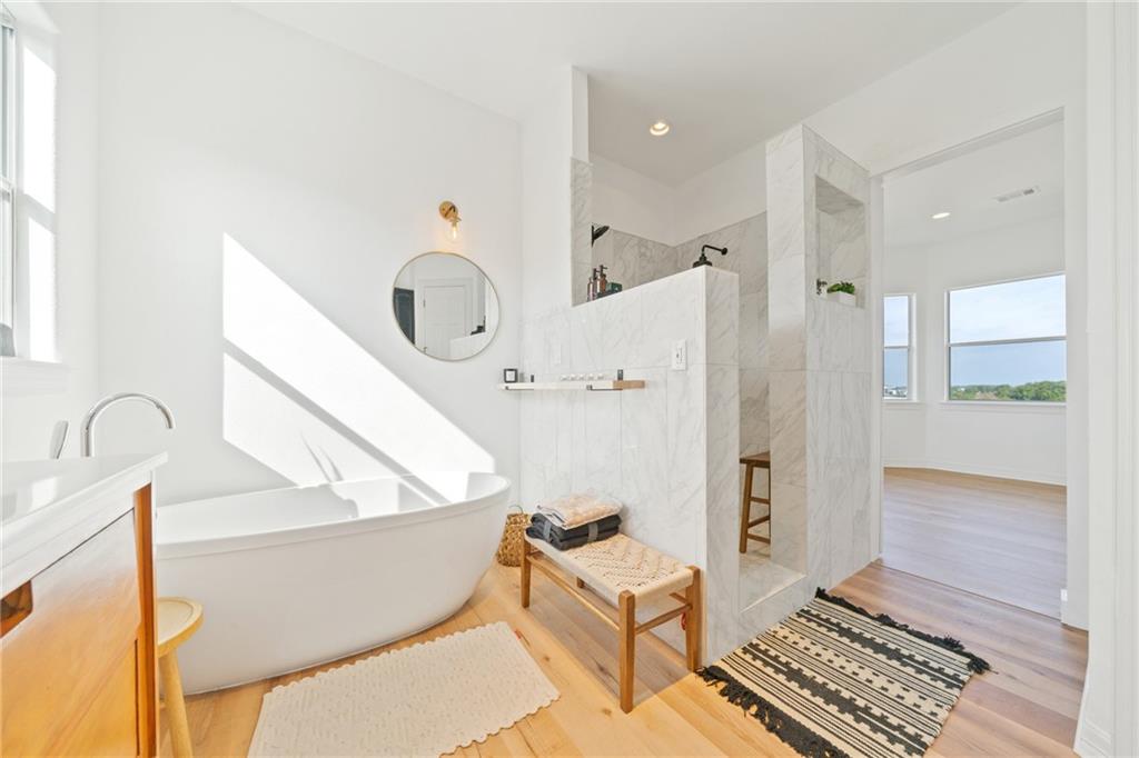 13301 Lone Rider Trail Bee Cave, TX 78738 - Photo 10 of 21 The bathroom features a freestanding soaking tub, a walk-in shower with tiled walls, and light wood flooring