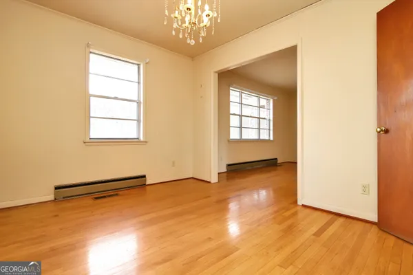 a view of an empty room with wooden floor and a bathroom