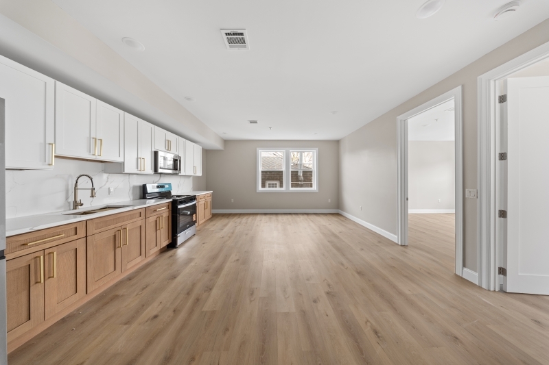 17 Wickham Street, Unit 203 Passaic, NJ 07055 - Photo 3 of 15 a large kitchen with cabinets wooden floor and stainless steel appliances