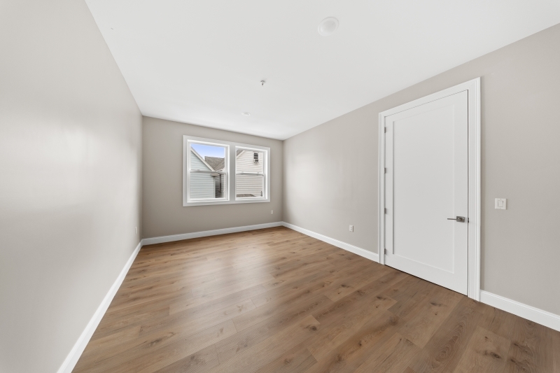 17 Wickham Street, Unit 203 Passaic, NJ 07055 - Photo 10 of 15 an empty room with wooden floor and windows