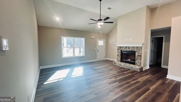 an empty room with wooden floor fireplace and windows