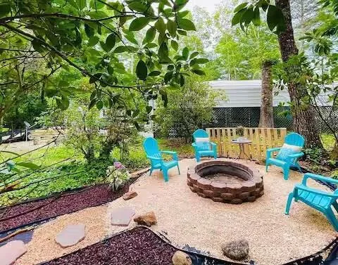 a view of a backyard with table and chairs potted plants and large tree