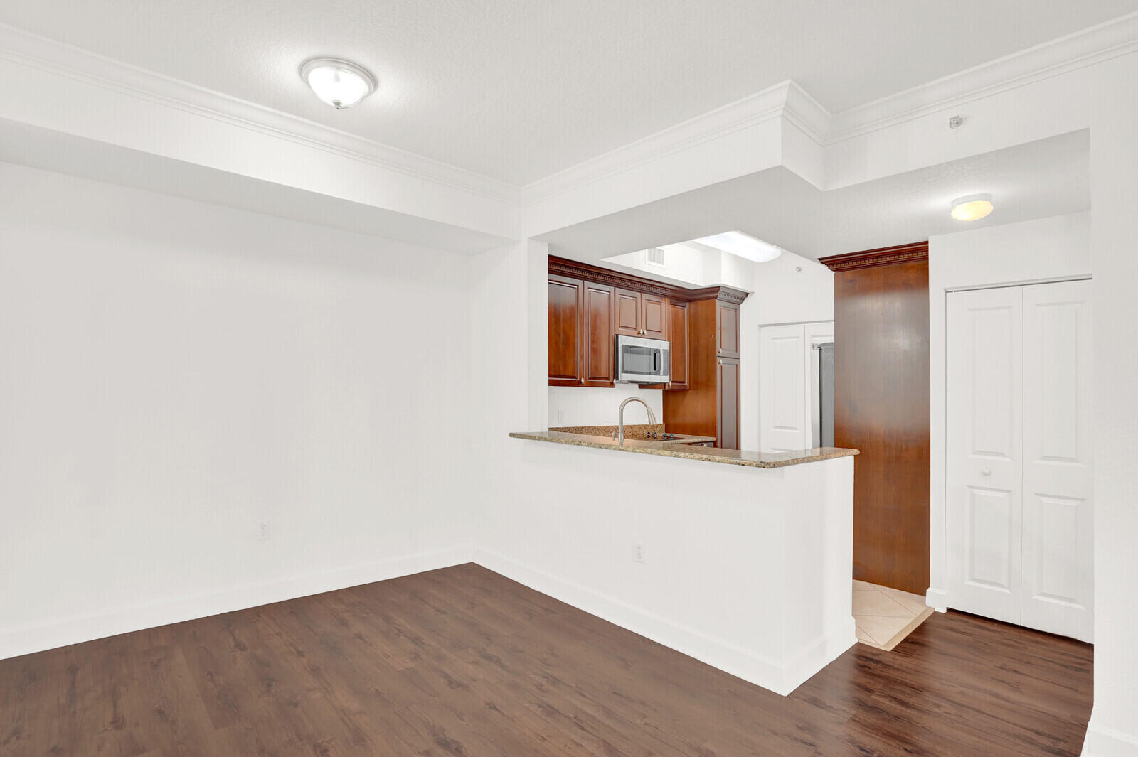 1690 Renaissance Commons Boulevard, Unit 1121 Boynton Beach, FL 33426 - Photo 2 of 32 a hallway with wooden floor table and chair