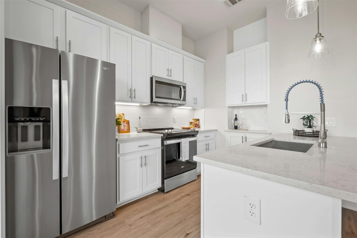 a kitchen with stainless steel appliances white cabinets a sink and a refrigerator
