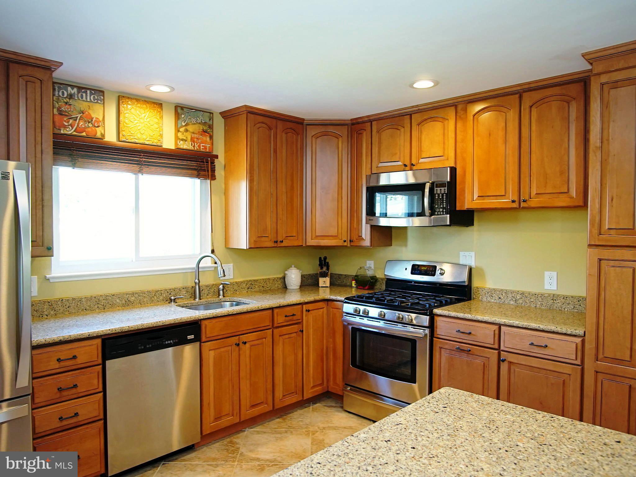6208 Collinsway Road Baltimore, MD 21228 - Photo 2 of 22 a kitchen with stainless steel appliances granite countertop a stove a sink dishwasher and a microwave oven with cabinets