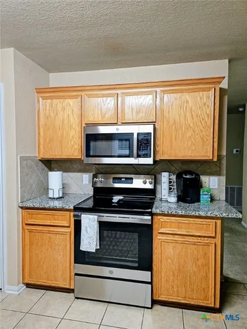 a kitchen with granite countertop a stove top oven cabinetry a sink and a microwave