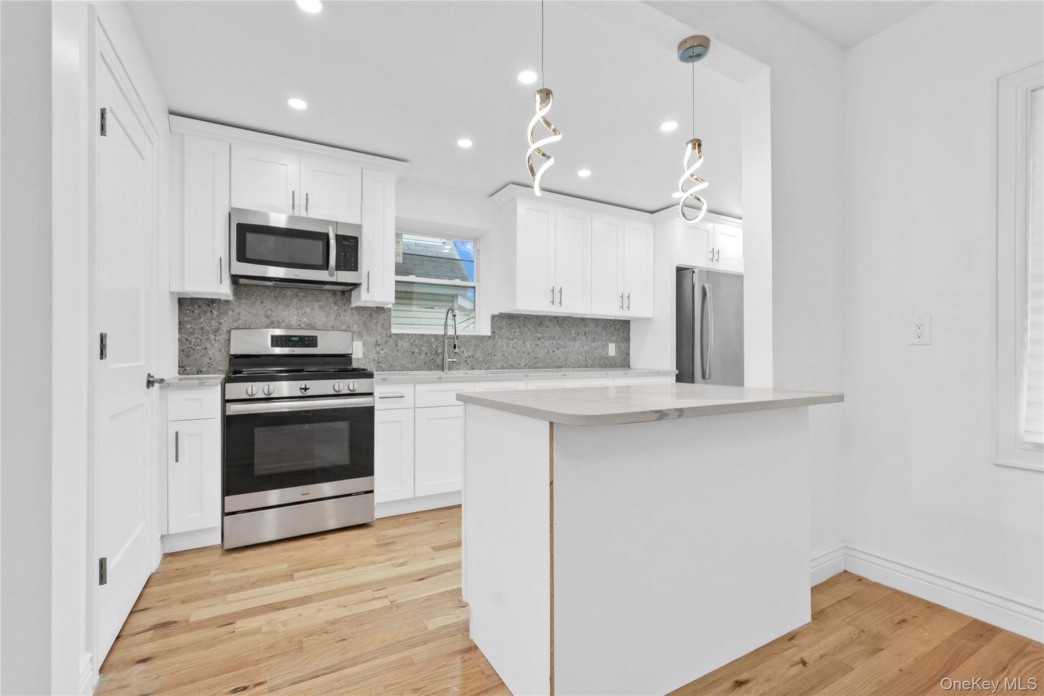 21432 112th Road Queens, NY 11429 - Photo 10 of 18 Kitchen featuring appliances with stainless steel finishes, recessed lighting, white cabinetry, hanging light fixtures, and tasteful backsplash