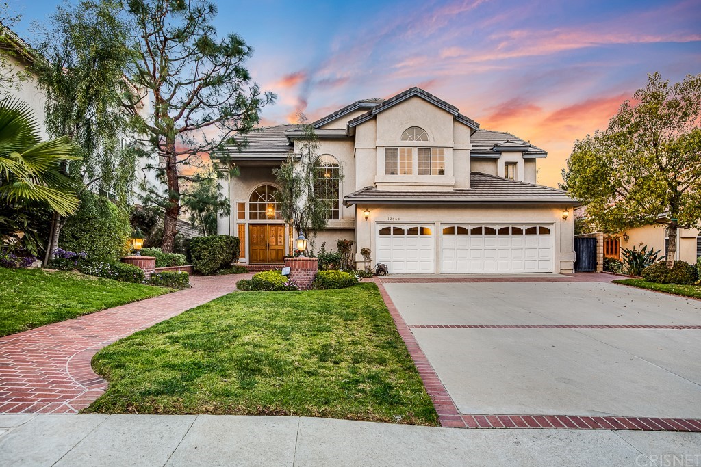 a view of white house with a big yard and large tree