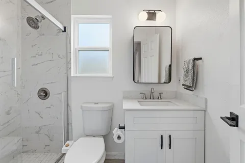 a bathroom with a toilet sink shower and mirror