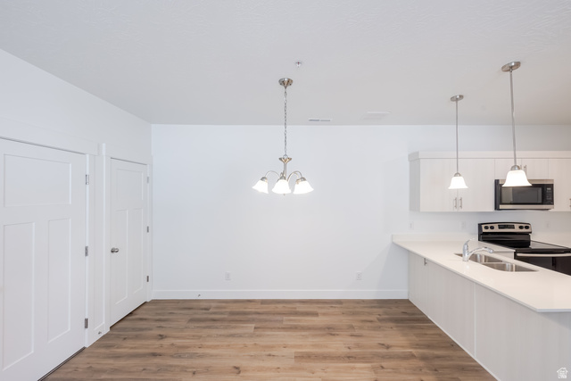 4727 South 690th West, Unit W203 Mapleton, UT 84664 - Photo 13 of 16 Wood-finish flooring throughout, white shaker cabinetry, stainless steel microwave, and pendant lighting