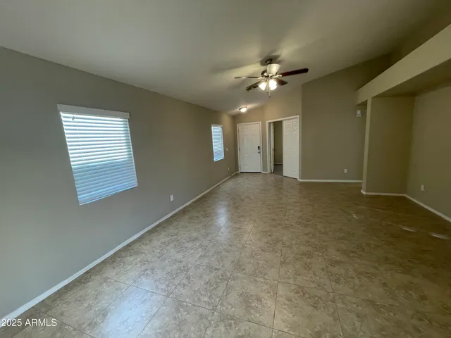 an empty room with windows and fan