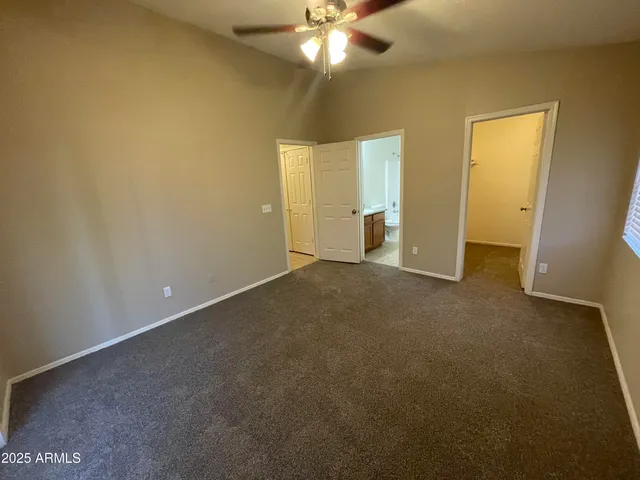 a view of an empty room and chandelier fan