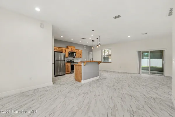 a view of a kitchen with kitchen island wooden floor and stainless steel appliances