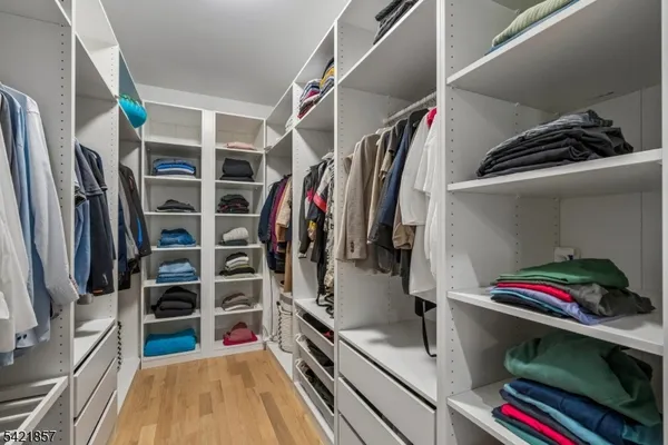 a view of walk in closet with clothes and shoes