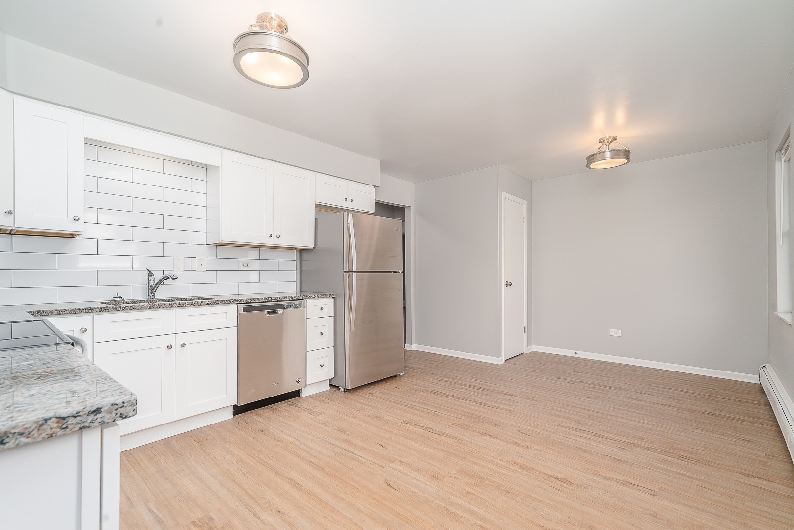 27 South Spring Avenue, Unit 2 La Grange, IL 60525 - Photo 6 of 13 a kitchen with granite countertop a refrigerator a sink dishwasher a stove and white cabinets with wooden floor