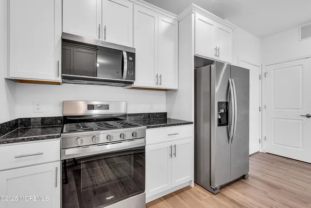 a kitchen with stainless steel appliances granite countertop a stove a refrigerator and a microwave