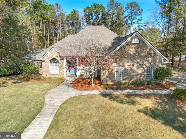 a view of house with yard and trees in the background