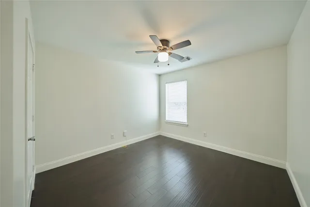 an empty room with a window and a ceiling fan