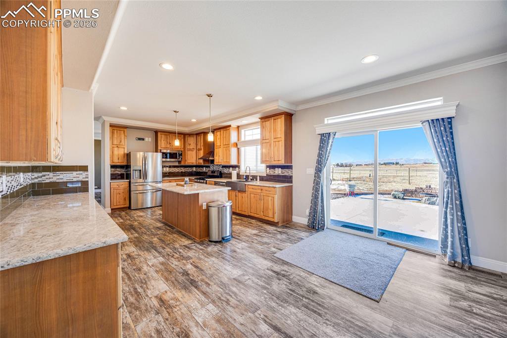 7880 J D Johnson Road Peyton, CO 80831 - Photo 11 of 50 Kitchen featuring a kitchen island, pendant lighting, stainless steel appliances, dark wood-style flooring, and light stone countertops