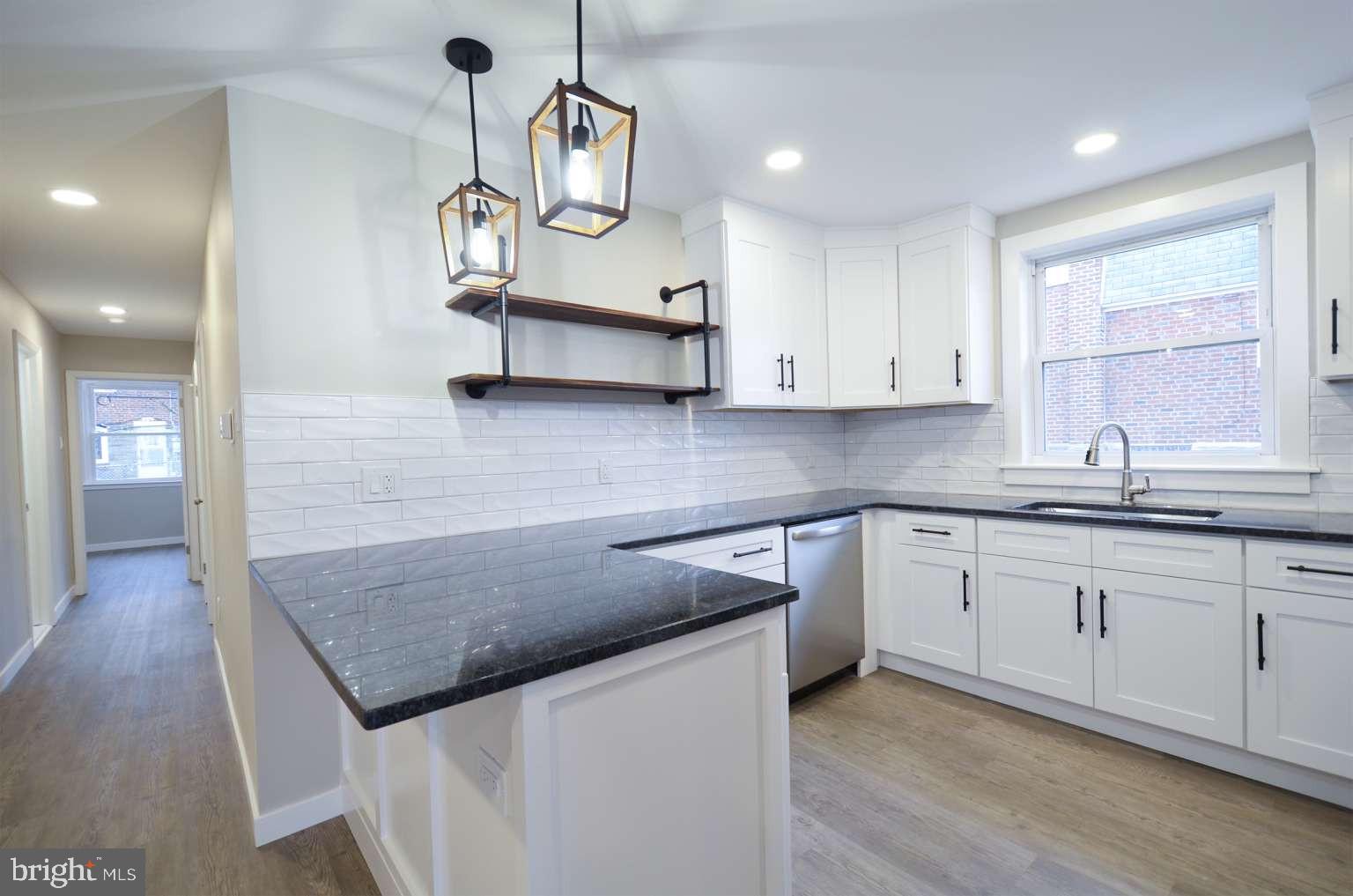8213 Colfax Street Philadelphia, PA 19136 - Photo 7 of 25 a kitchen with stainless steel appliances granite countertop a sink dishwasher and white cabinets with wooden floor