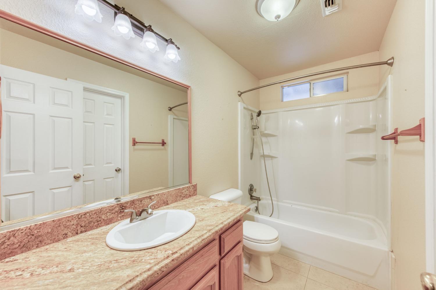 8062 Monreal Drive Sanger, CA 93657 - Photo 11 of 24 a bathroom with a granite countertop sink toilet a mirror and shower