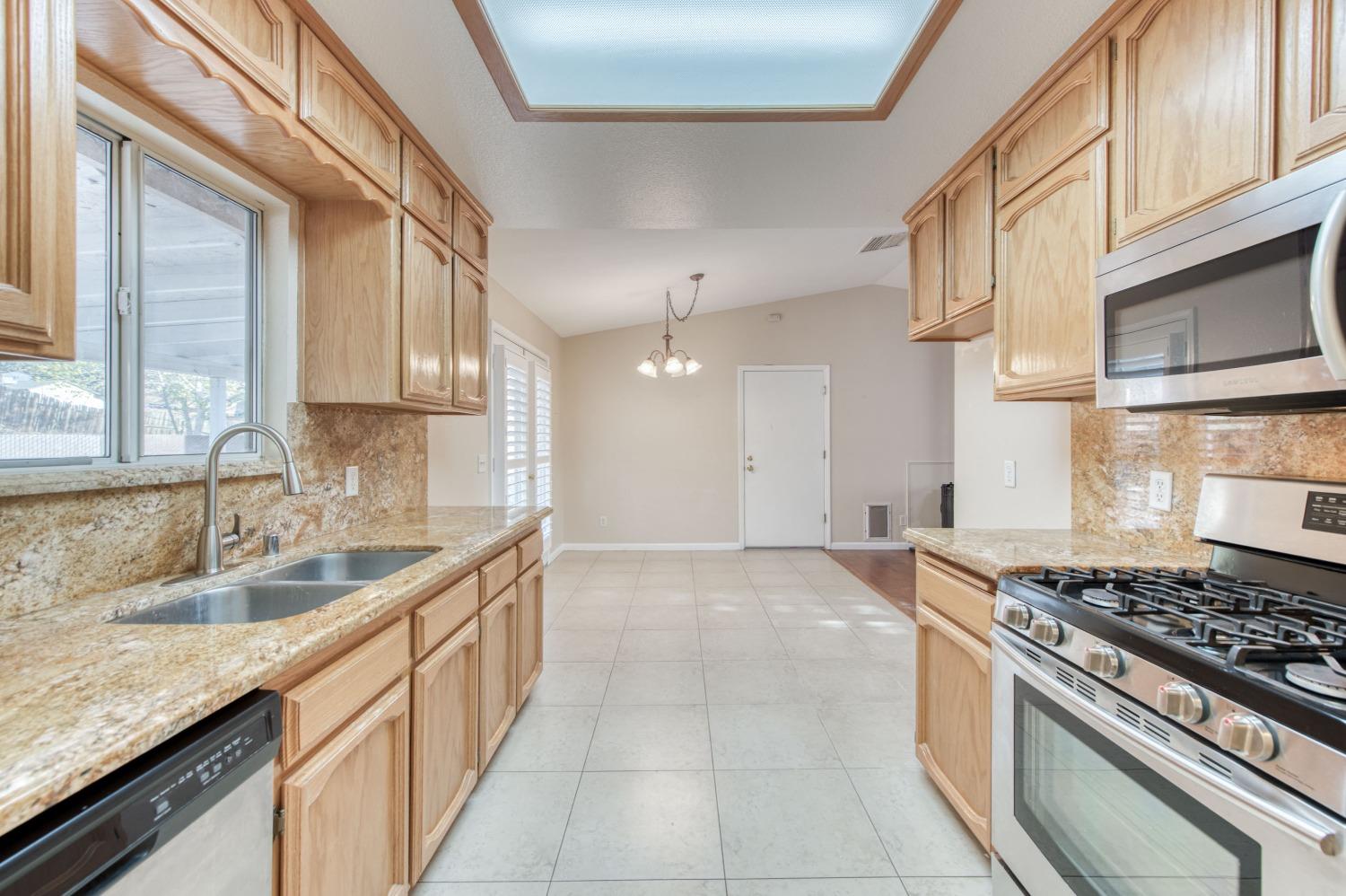 8062 Monreal Drive Sanger, CA 93657 - Photo 4 of 24 a kitchen with stainless steel appliances granite countertop a sink and a stove