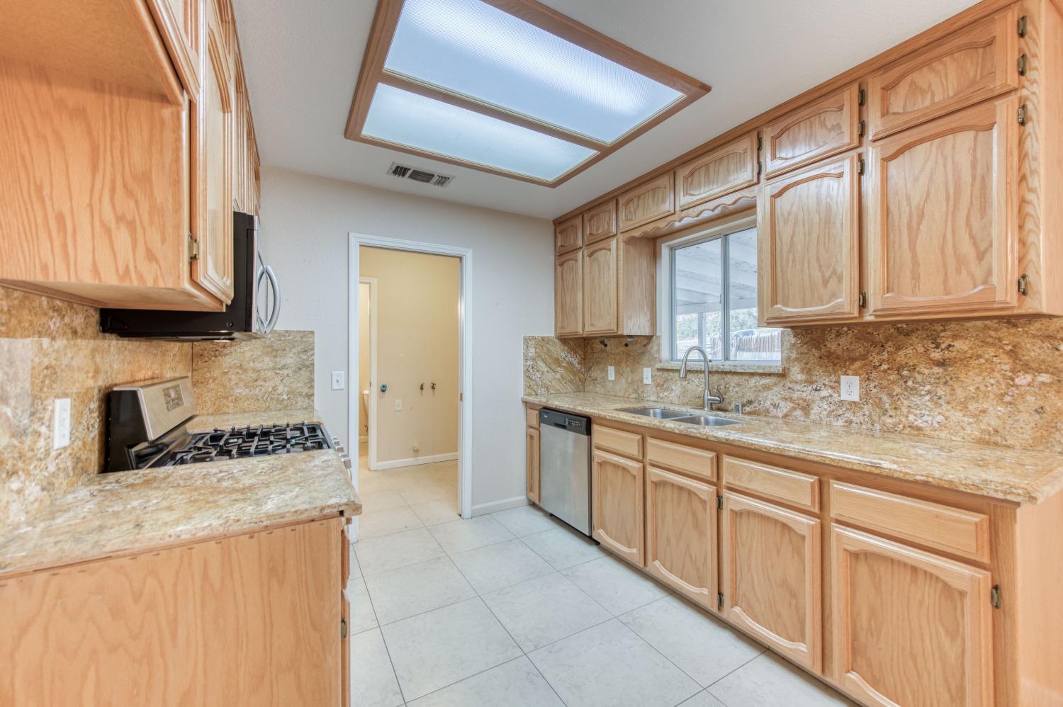 8062 Monreal Drive Sanger, CA 93657 - Photo 9 of 24 a kitchen with stainless steel appliances granite countertop a sink and cabinets