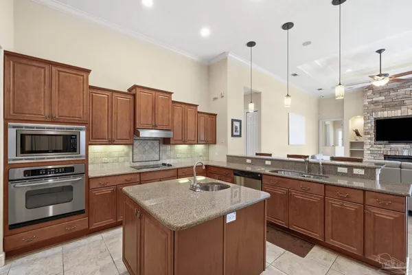 a kitchen with stainless steel appliances kitchen island granite countertop a dining table chairs and a refrigerator