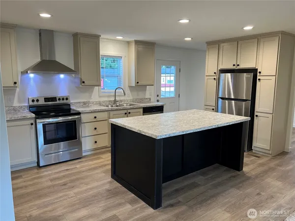 a kitchen with kitchen island a sink dishwasher stove and refrigerator with wooden floor