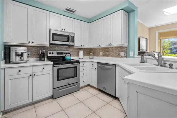 a kitchen with white cabinets stainless steel appliances and sink