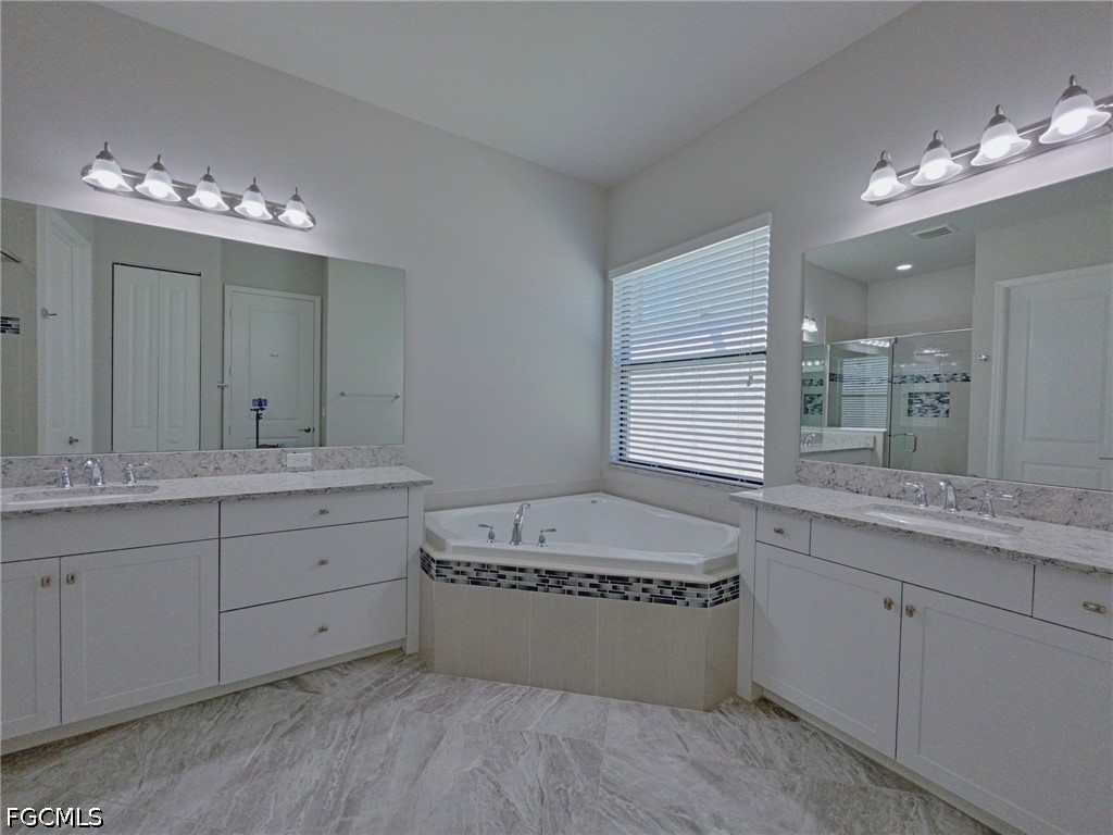 4129 Amelia Way Naples, FL 34119 - Photo 11 of 23 a bathroom with a tub double sink and a large mirror