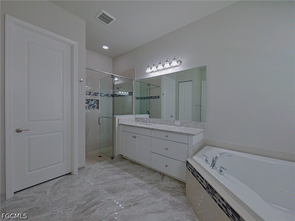 4129 Amelia Way Naples, FL 34119 - Photo 12 of 23 a bathroom with a tub sink double vanity granite and a mirror