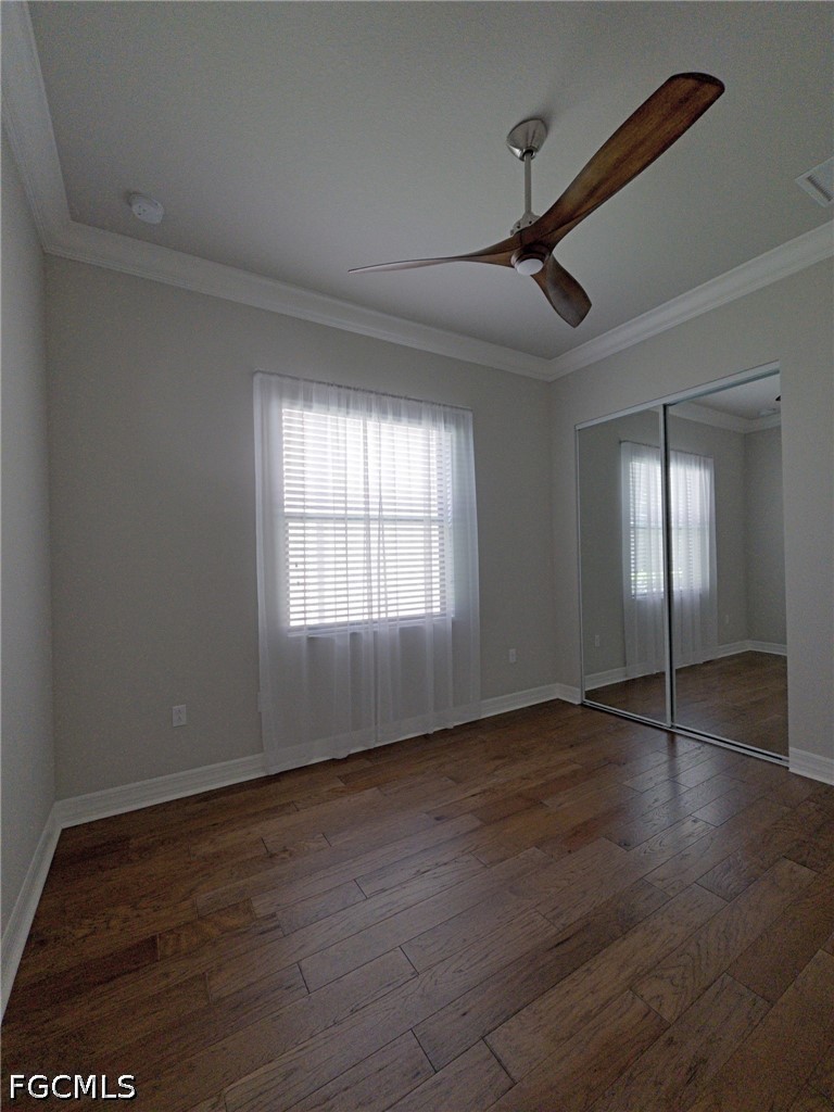 4129 Amelia Way Naples, FL 34119 - Photo 15 of 23 an empty room with wooden floor and windows